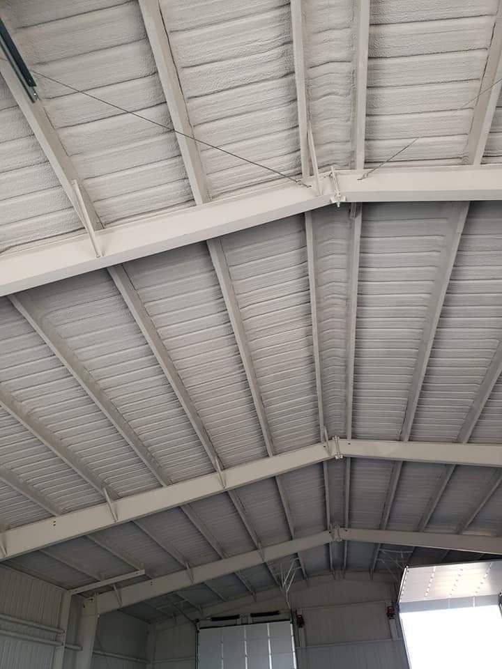Metal building roof structure insulated with spray foam