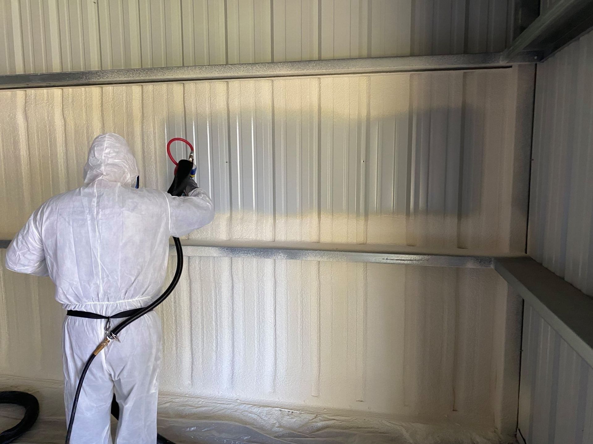 Volunteer FoamPros technician spraying closed cell foam onto a metal building wall