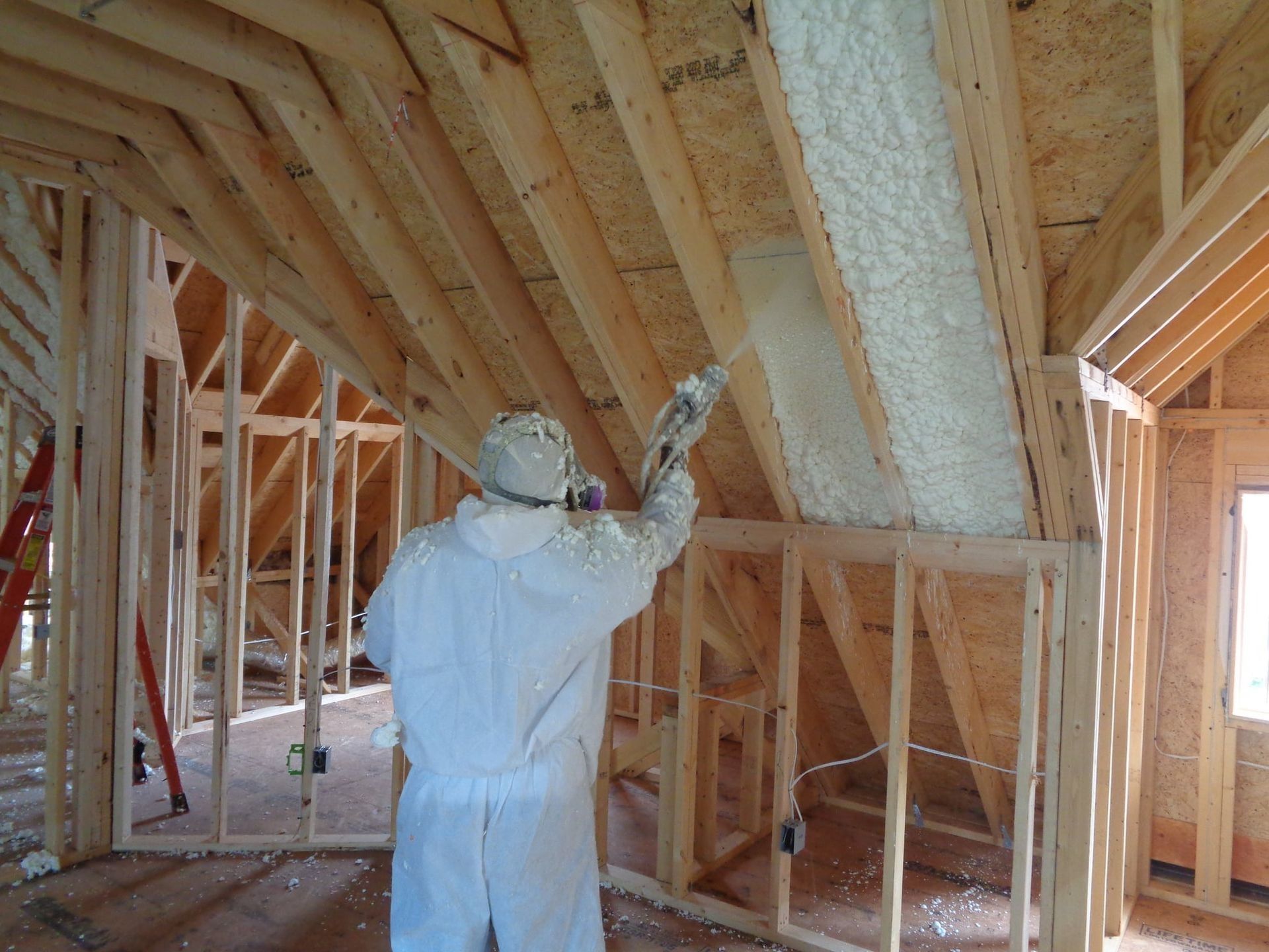 Technician spraying foam insulation into a gable end wall