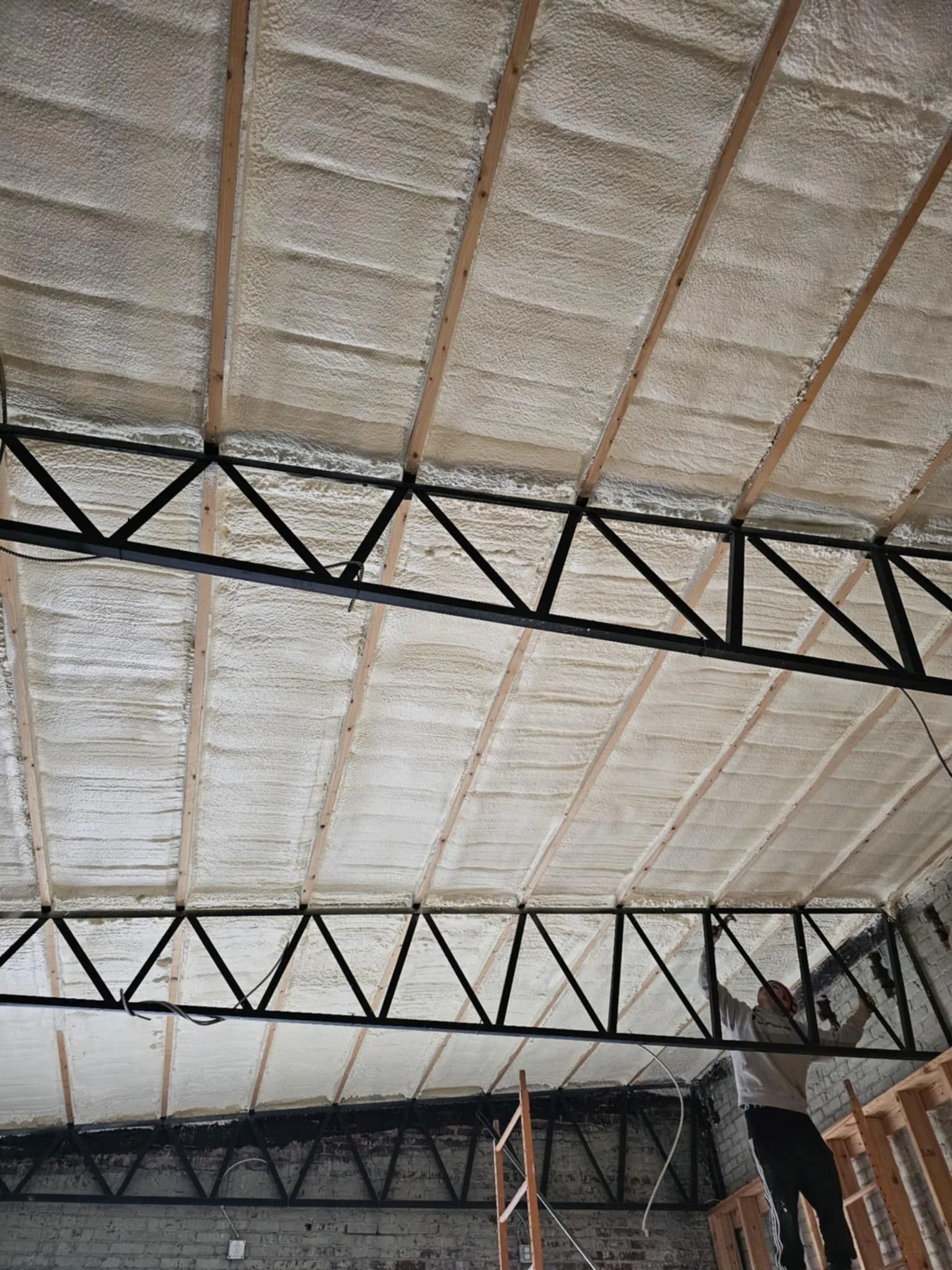 Spray foam insulation on the trusses of a steel frame building